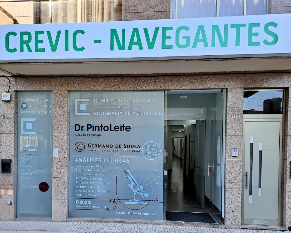Fachada de uma clínica de radiologia e ecografia, CREVIC, que também tem serviços de análises clínicas em parceria com o Germano de Sousa. Há montras de vidro com os serviços listados.